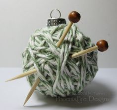 an ornament made out of yarn with two knitting needles sticking out of it