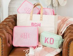 three personalized bags sitting on top of a brown chair next to a pink blanket