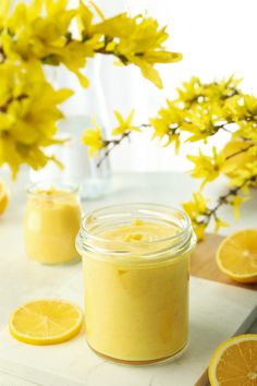 a jar filled with yellow liquid next to sliced lemons