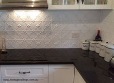 a kitchen with white cabinets and black counter tops is pictured in this image, there are several coffee mugs on the counter