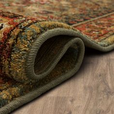 an area rug is laying on the floor with it's end rolled up to reveal a corner