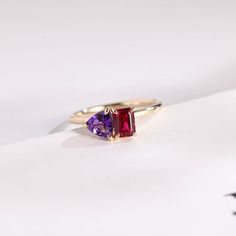 a gold ring with two different colored stones on the front and back, sitting on a white surface