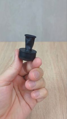 a hand holding a small black object on top of a wooden table