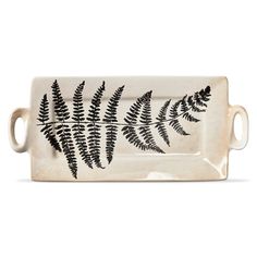 a white and black tray with a fern design on the front, sitting on a white surface