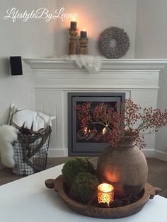 a candle is lit on a tray with flowers and candles in front of a fireplace