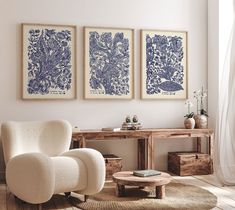 three blue and white prints hang on the wall above a chair in a living room