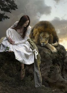 a woman sitting on top of a rock next to a lion in front of a cloudy sky