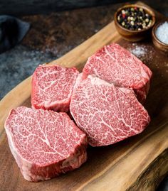 raw steaks on a cutting board with salt and pepper