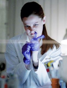 a woman in white shirt and purple gloves holding up her hand to the side with words on it