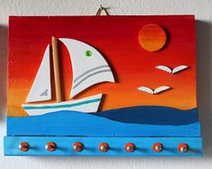 a wooden wall hanging with a sailboat and seagulls painted on it's side