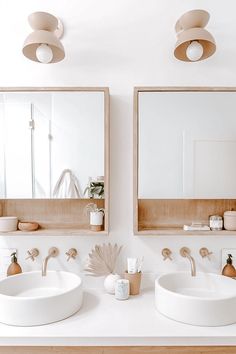 two sinks in a bathroom with mirrors and lights on the wall above them, next to each other