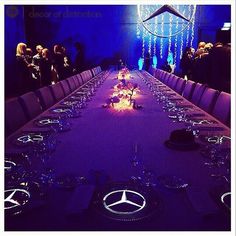 a long table is set up for a formal dinner with purple lighting and chandeliers