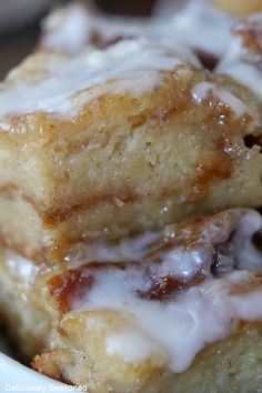 two pieces of cinnamon roll with icing in a white bowl