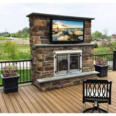 a television mounted to the side of a brick fireplace on top of a wooden deck