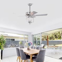 a dining room table with chairs and a ceiling fan in the middle of an open floor plan