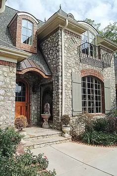 a large stone house with lots of windows and shutters on the front door is shown