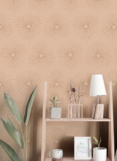 a shelf with some plants on top of it next to a lamp and wallpaper