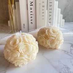 two candles with roses on them sitting next to books