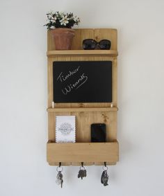 a blackboard mounted to the side of a wooden shelf with key hooks and keys