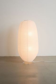 a white lamp sitting on top of a floor next to a wall