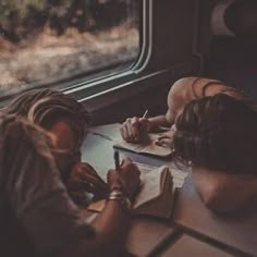 two people sitting on a train looking out the window at something in front of them