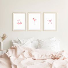 three framed pictures hang on the wall above a bed with pink linens and pillows