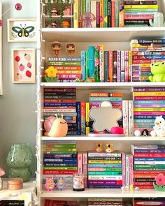 a bookshelf filled with lots of colorful books and stuffed animals on top of it