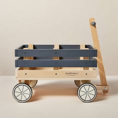 a wooden toy wagon with wheels on a white surface