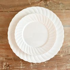 two white plates sitting on top of a wooden table