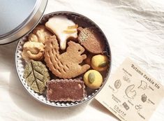 a metal bowl filled with different types of cookies next to a paper label on a table