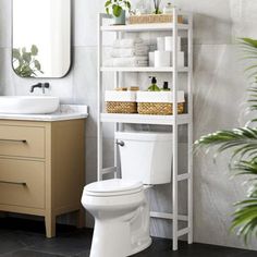 a white toilet sitting in a bathroom next to a sink and a shelf filled with towels