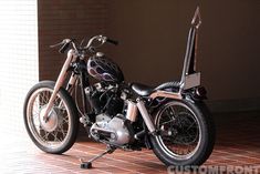 a black motorcycle parked on top of a brick floor next to a white and brown wall