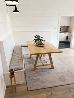 a wooden table sitting on top of a hard wood floor next to a white wall