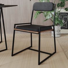 two black chairs sitting next to each other on top of a wooden floor in front of a plant