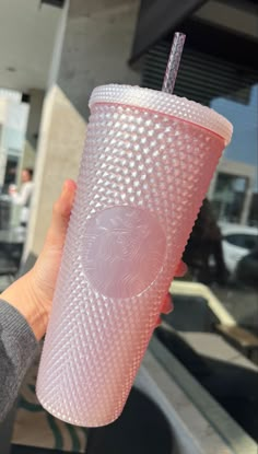 a person holding up a pink starbucks cup