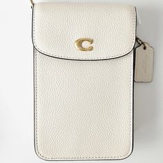 Coach Phone Crossbody Bag Color: Brass/Chalk Product Details Materials : Polished Pebble Leather Fabric Lining Strap : Detachable Strap With 21.5" Drop For Shoulder Or Crossbody Wear Features : Outside Open Pocket Two Credit Card Slots Snap Closure Measurements : Length: 4.5" Height: 7.25" Width: 1.0" Fits All Phone Sizes Up To An Iphone X And Samsung S7 Edge Comes From A Non-Smoking Home. Please Note That The Measurements Of The Item Will Be Approximate Sizes. Color Of The Item Might Be Slightl White Luxury Shoulder Bag With Mobile Phone Holder, White Crossbody Shoulder Bag With Mobile Phone Pocket, Luxury White Shoulder Bag For On-the-go, White Coach Shoulder Bag For On-the-go, Cream Crossbody Mobile Phone Bag, White Rectangular Phone Bag With Cell Phone Pocket, White Leather Phone Bag For Daily Use, Classic White Mobile Phone Bag, White Everyday Use Phone Pouch Bag