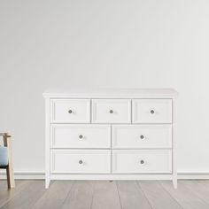 a white dresser sitting on top of a hard wood floor next to a blue chair