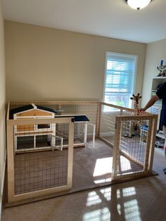 a man standing next to a caged in animal house on top of a carpeted floor