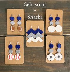 six pairs of earrings with different designs on them sitting in front of a wooden table