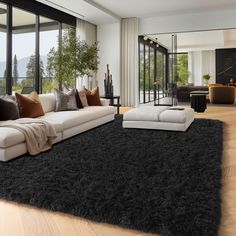 a modern living room with large windows and black rugs on the hardwood flooring