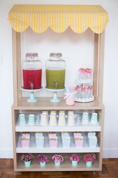 a wooden shelf filled with cupcakes and drinks