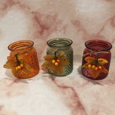 three glass jars with leaves and berries on them