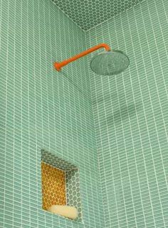 a green tiled shower with an orange handle in the corner and a hole in the wall