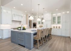 a large kitchen with white cabinets and gray island counter tops, surrounded by wicker chairs