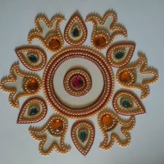 a circular design made with gold, green and red stones on a white surface in the shape of a flower