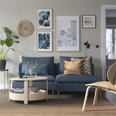 a living room with blue couches and pictures on the wall above them in various frames