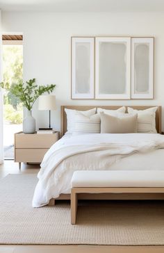 a bed with white linens and pillows in a bedroom next to two pictures on the wall