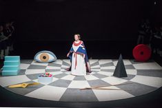 a woman standing on top of a checkered floor in front of an evil eye