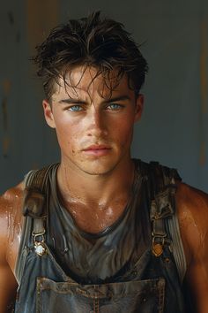 a young man in overalls with wet hair and blue eyes looking at the camera