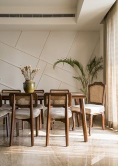 a dining room table with chairs and a vase filled with flowers on top of it